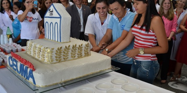 Professora, colaboradora e estudante cortando o bolo comerativo