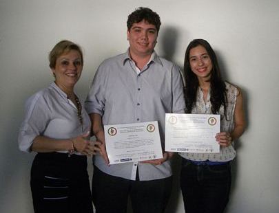 Entrega do certificado de apresentação pela Profa. Dra. Andrea Pires, para os alunos Matheus Cardoso Silva e Ana Paula Ahid